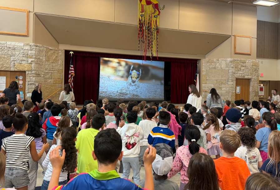 Students standing up looking at screen with a spider dancing