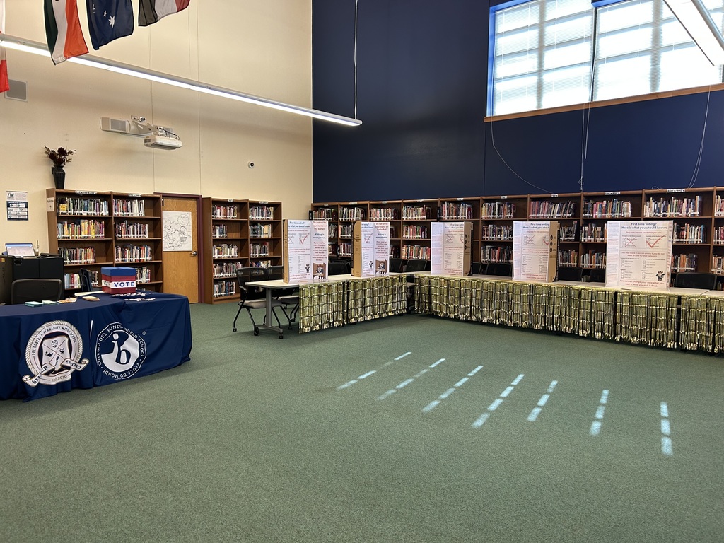 Voting booths and the table with a ballot box that says 'Vote' and the Hernandez and IB logo on a blue tablecloth.