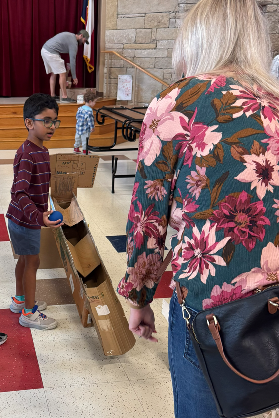 Photo of boy holding ball beside cardboard game