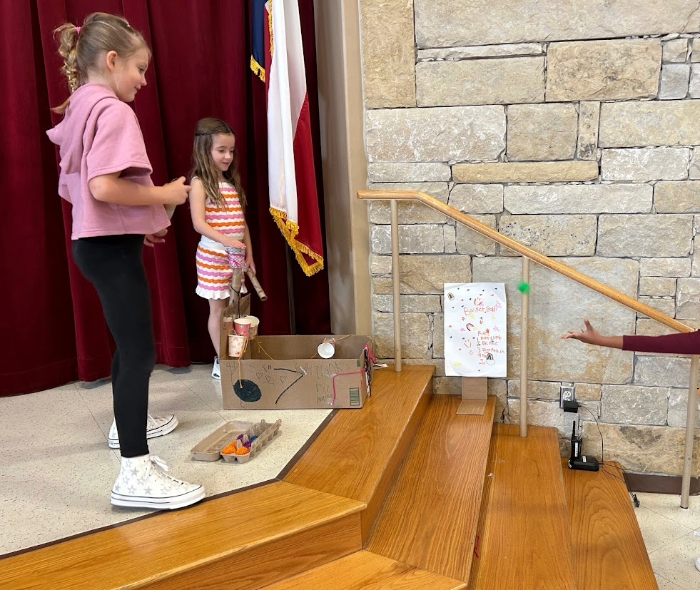 Picture of two girls standing beside a cardboard game