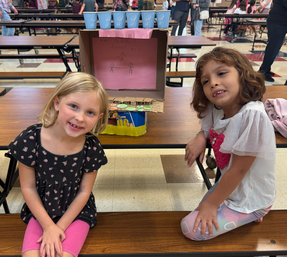 Picture of two girls sitting by cardboard game