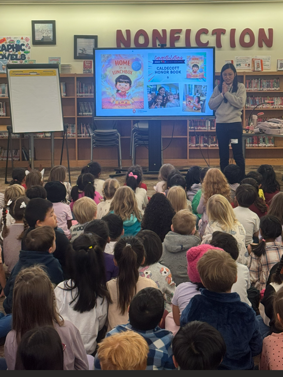 Author Cherry Mo standing by screen in front of students