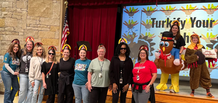 Teachers wearing turkey hats and costumes standing beside eachother