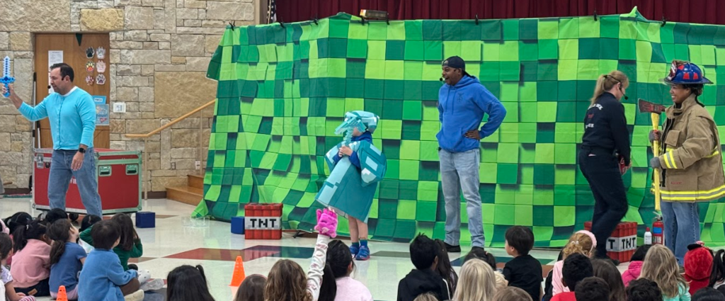 3 adutls and one student standing in front of green backdrop. One person is dressed in firefighter gear