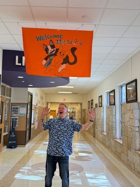 Author John Schu standing under sign