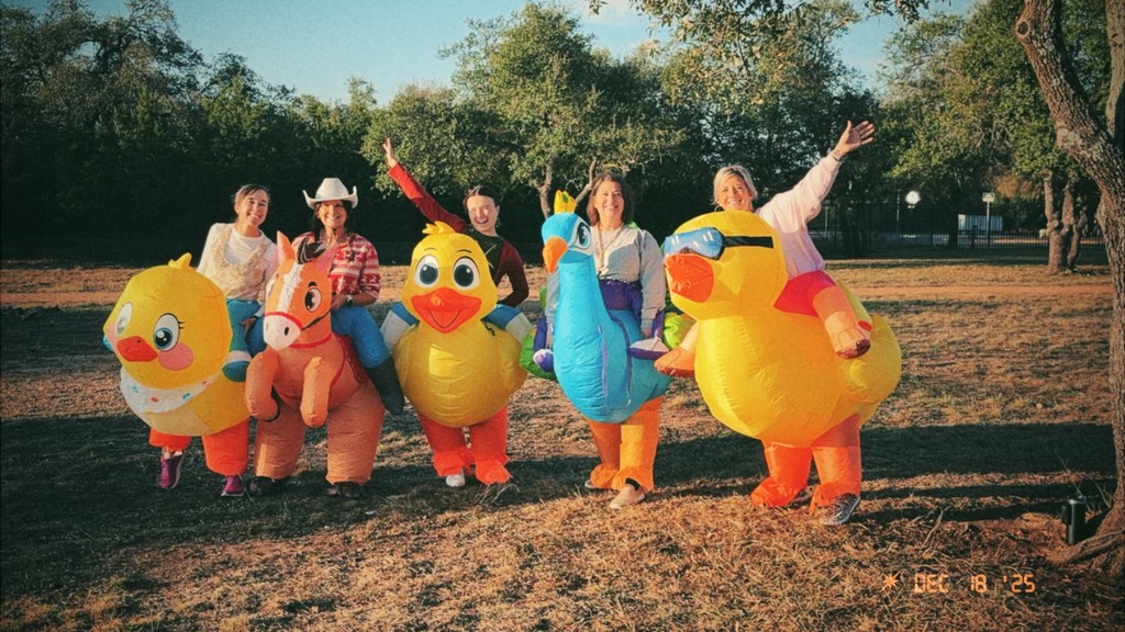 Teachers standing dressed in inflatable costumes in front of trees