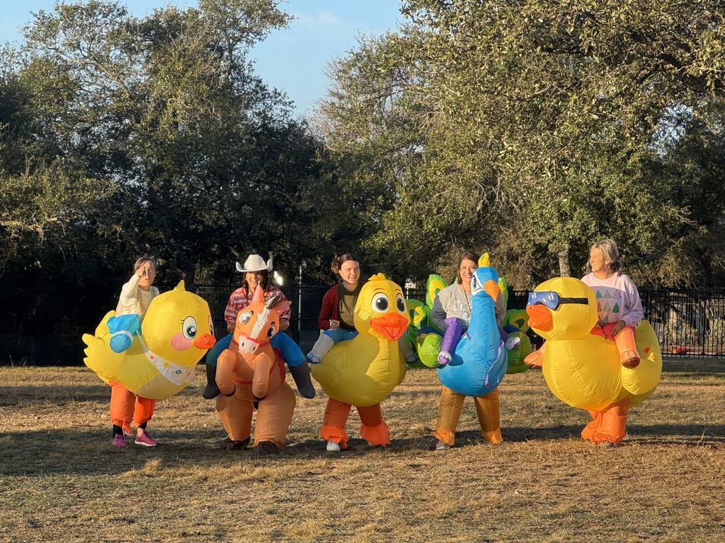 Teachers standing dressed in inflatable costumes in front of trees