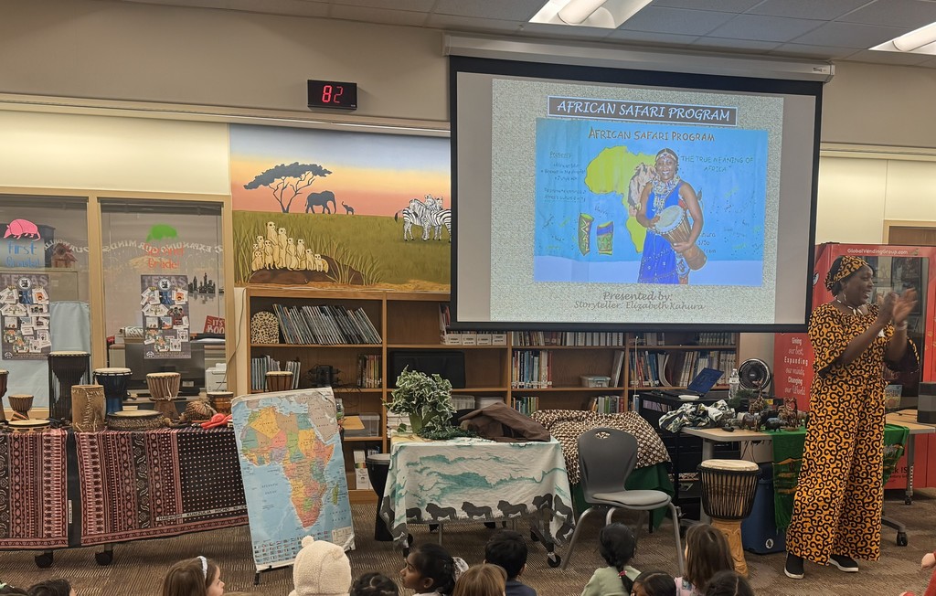 Instruments sitting on table, map of Africa displayed, African storyteller in front of screen