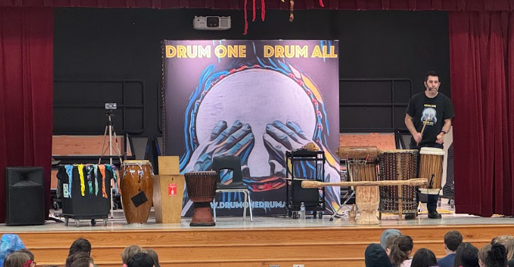Man playing drums on a stage with various drums