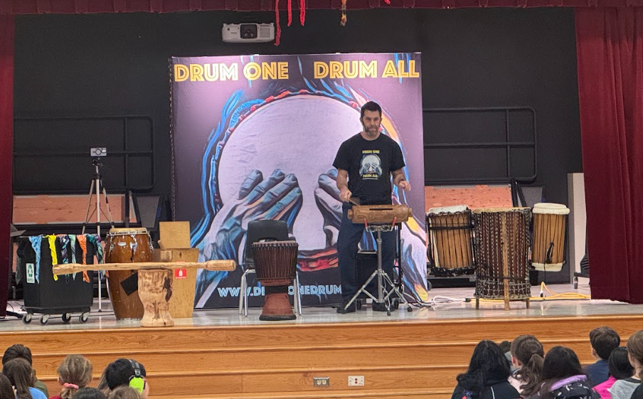 Man playing drums on a stage with various drums