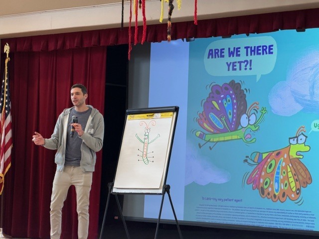 Author Ross Burach standing in front of easel and screen