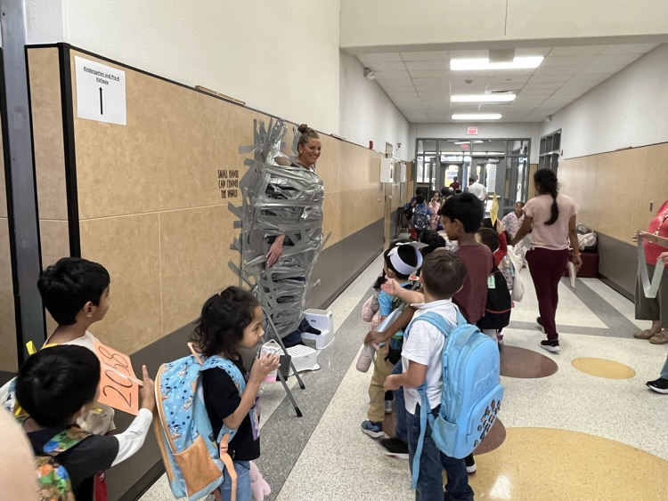 students looking at principal taped to wall 