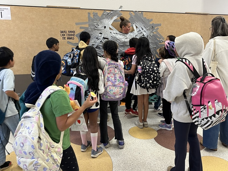 students looking at principal taped to wall