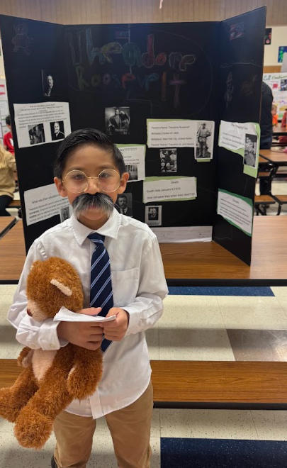 Photograph of student standing in front of table with trifold board on it
