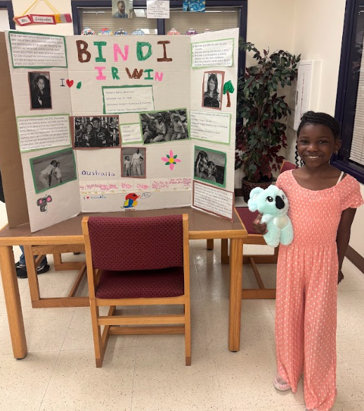 Photograph of student standing in front of table with trifold board on it