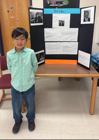 Photograph of student standing in front of table with trifold board on it