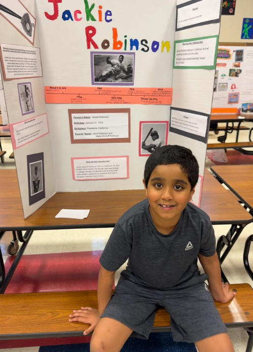 Photograph of student sitting in front of table with trifold board on it