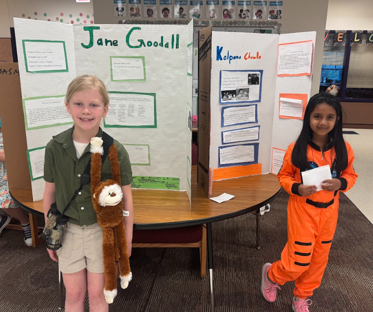 phtograph of two students standing in front of table with trifold boards on it