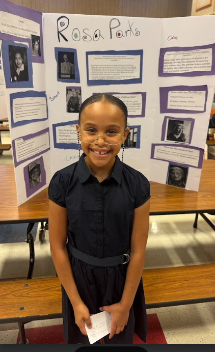 Photograph of student standing in front of table with trifold board on it