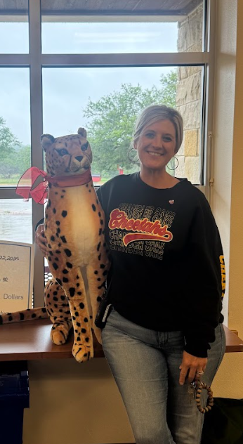 Photograph of Principal Vanessa Randels holding a stuffed cheetah in front of a window