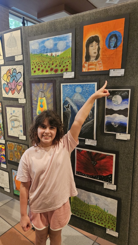 Student pointing to her artwork. 