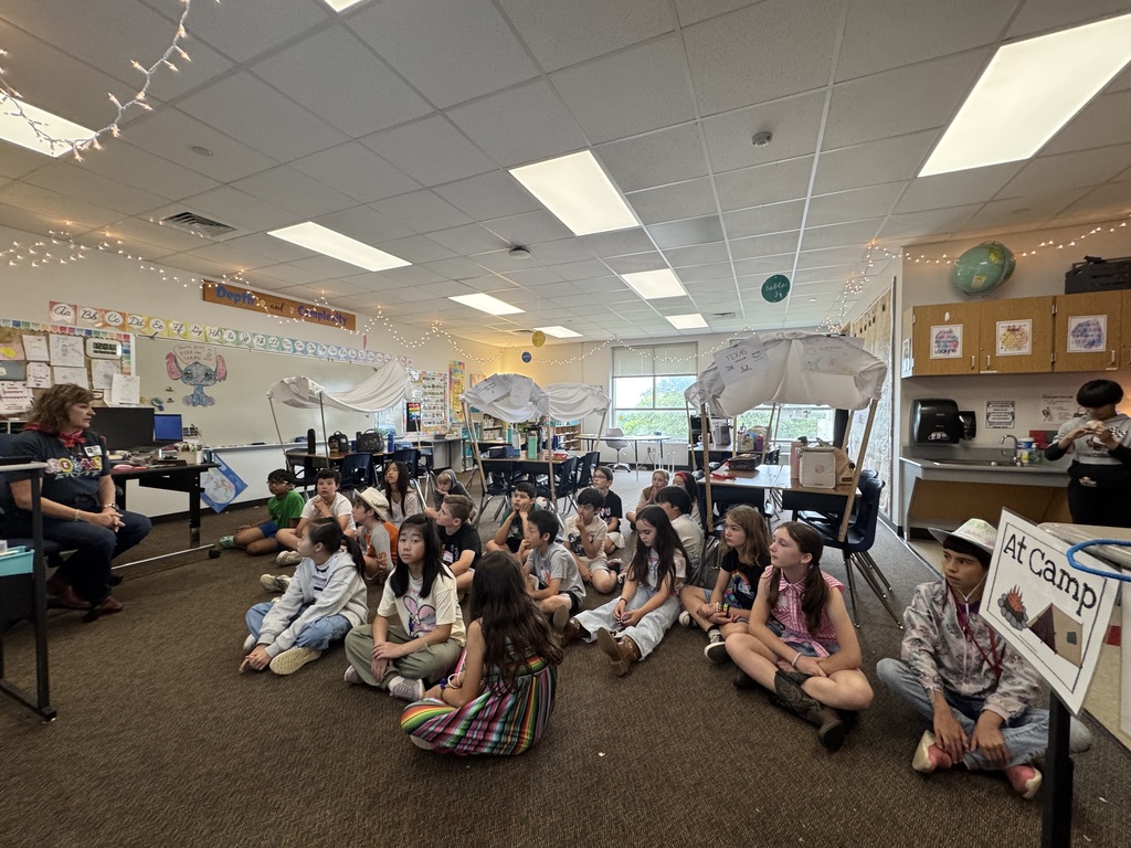 Students in a classroom with covered agons listening to the teacher. 