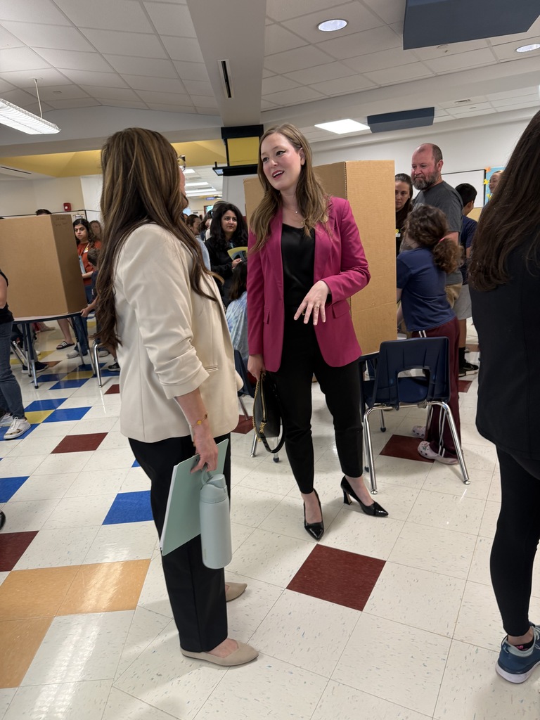 Representative Caroline Harris Davila speaks with Ms. Borunda in the Blackland Prairie Elementary cafeteria during the Leadership Day event surrounded by students and families.