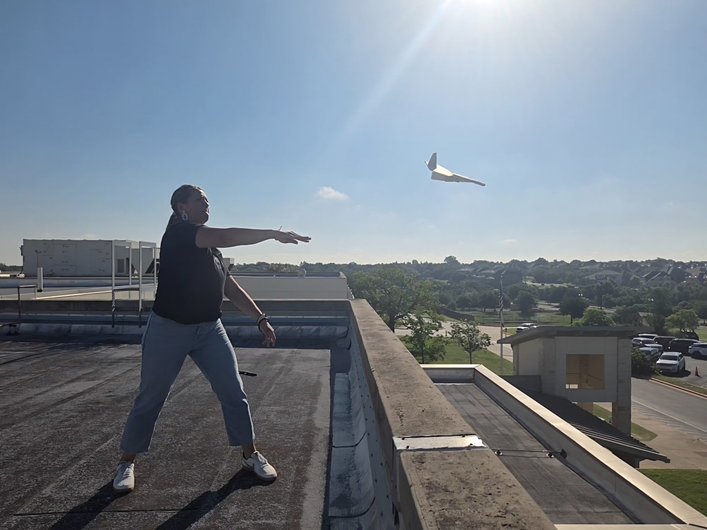 Ms. Elarms throwing a plan and it soaring in the sky. 