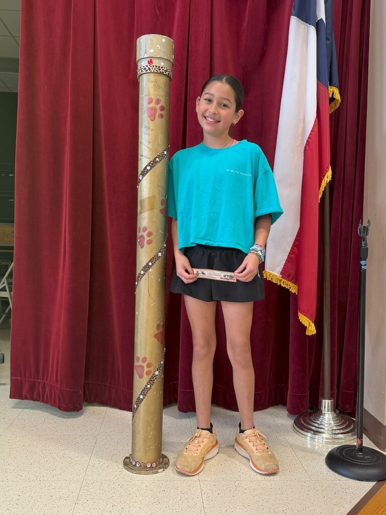 Student standing next to a decorated large gold tube