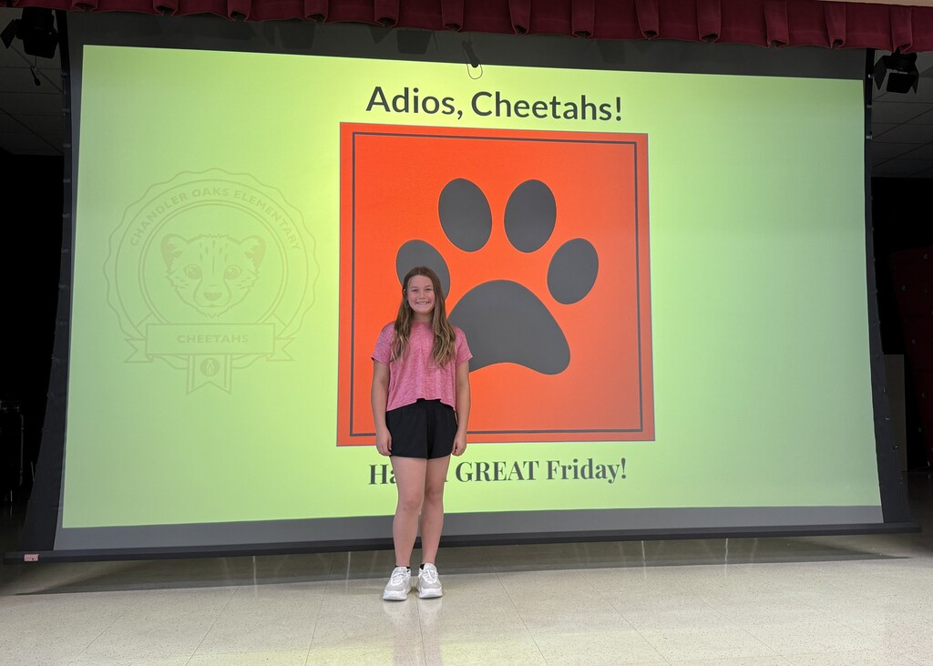 Student standing in front of screen that has a red square with a paw on it with the words "Adios, Cheetahs!" on the top and "Have a GREAT Friday! on the bottom