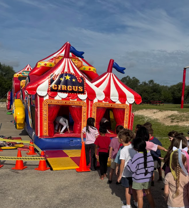 Photograph of students waiting in line to get onto the circus themed inflatable
