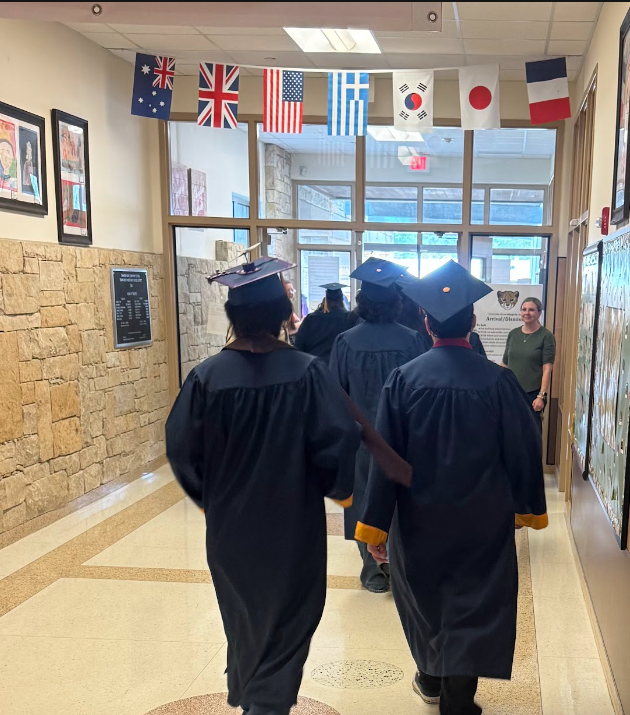 Senior students dressed in Navy Blue Cap and gowns exiting the front doors of the school entance