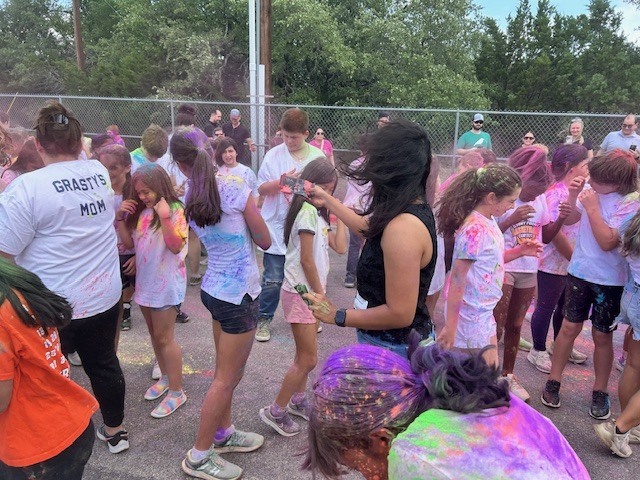 Many students standing on road covered in different colored dyes
