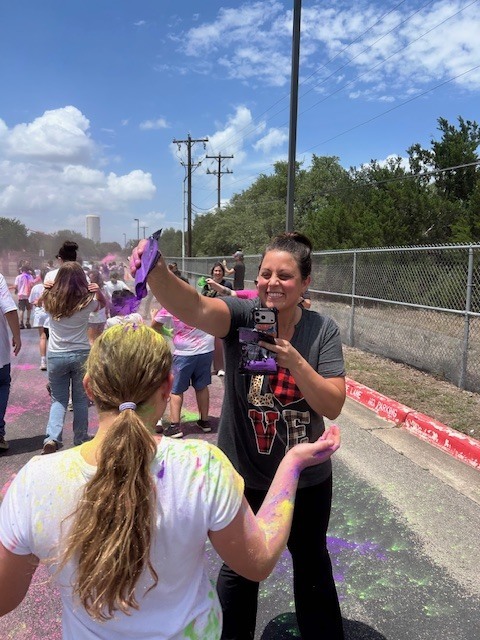 An adult dumping purple dye onto head of girl outside on the street