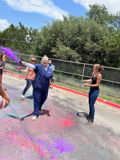 An adult throwing purple dye next to other adultes