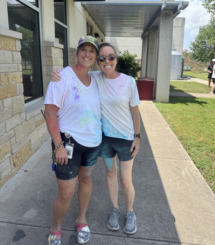 Principal and Assistant Principal standing outside on sidewalk covered in different colored dyes