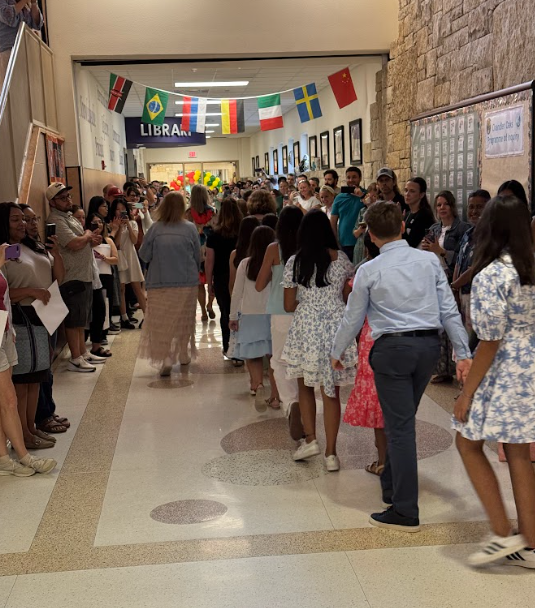 Students walking down the hallway lined with parents for the 5th grade walk