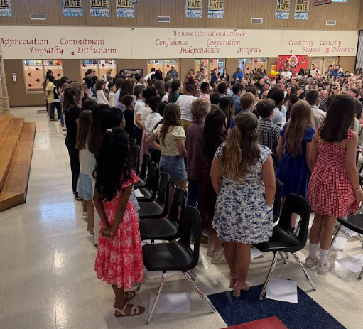 Photograph of 5th grade students standing up facing the parents singing the school song
