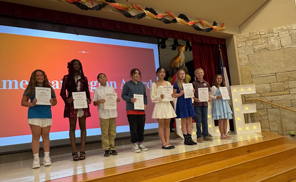 8 students who received the American Legion Awards standing on the stage holding a certificate