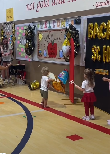 Two children standing facing "Back to School" Decorations and balloons