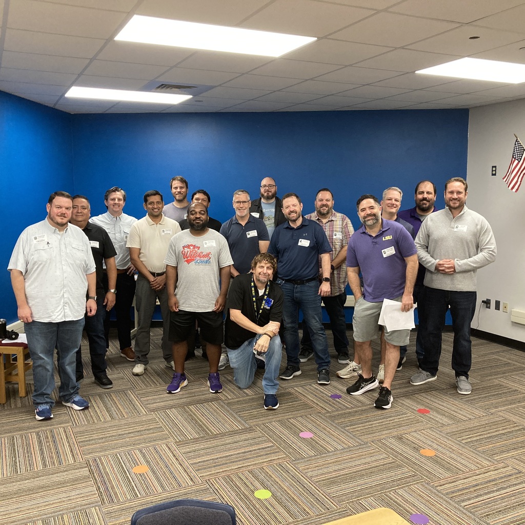 A group of volunteer Wildcat Dads smiling and posing together in a classroom after teaching fifth grade science.
