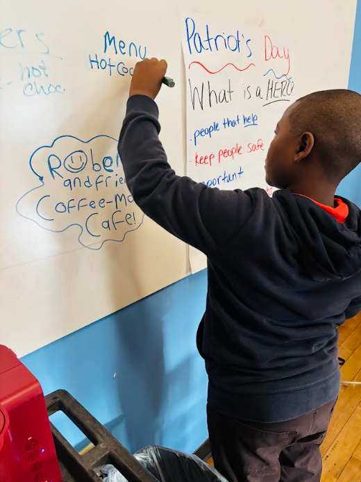 A student writing "Menu: Hot chocolate" on a white board