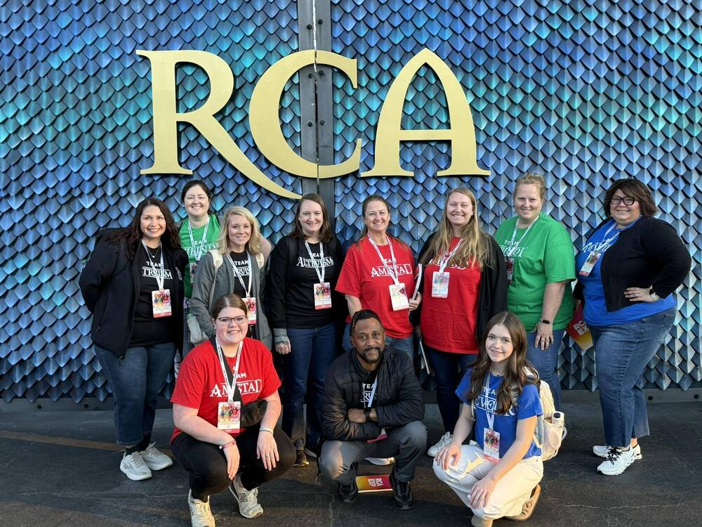 Pictured left to right, Back row: Ashley Bailey, Lori Meadows, Amanda Carter, Melanie Winstead, Chari Denny, Sarah Albachten, Kara Roberts, Alex Porter. Front row: Hannah Buchanan, Jamel Jones, and Piper Shearin. All posing in front of a gate that looks like it's covered in dragon scales and the letters RCA on it.