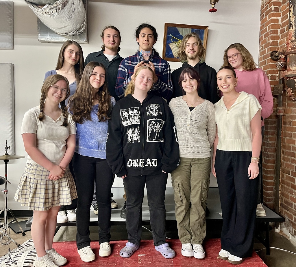 RCS high school senior band students pose together holding a clear trophy in the RCS band room.