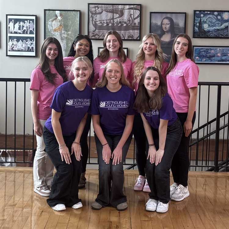 8 female students pose together, smiling in pink and purple tshirt.