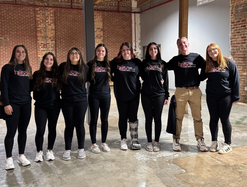 8 students stand in a line posing together wearing their HOSA t-shirts. 