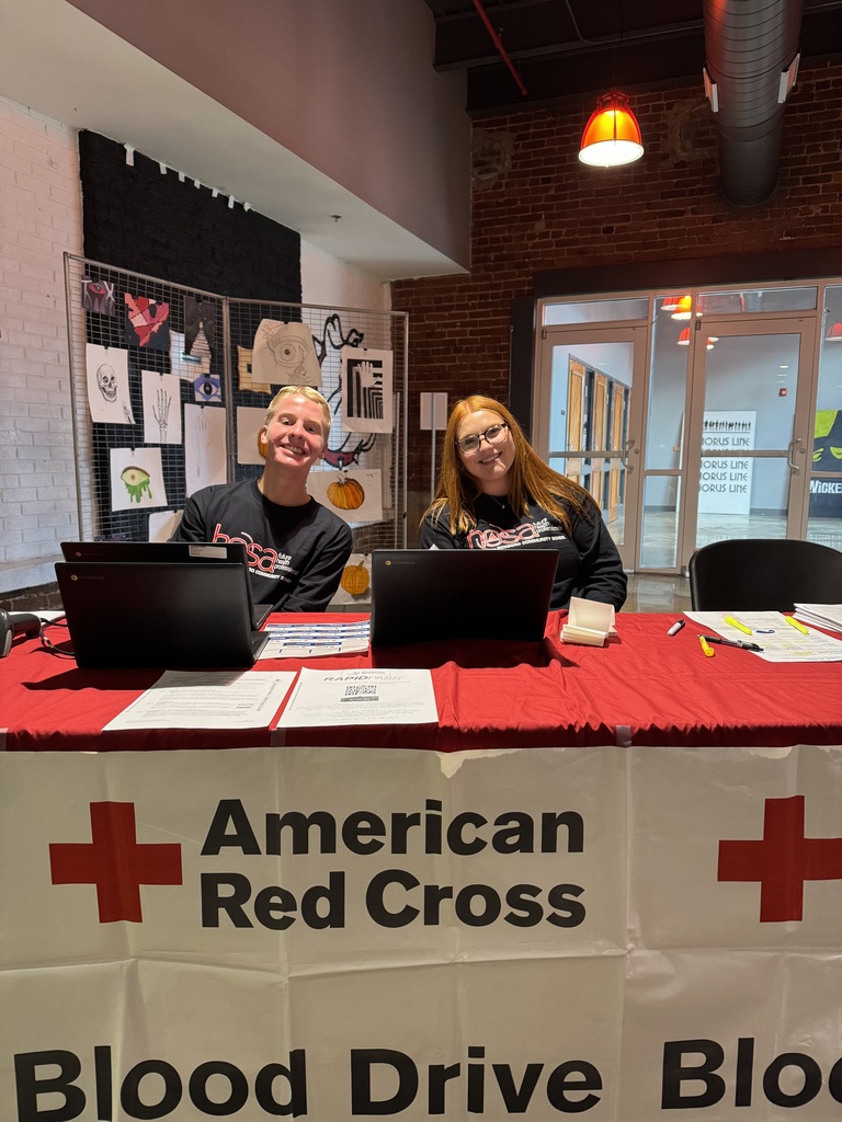 A male and a female student sitting at a table with laptops in front of them. 