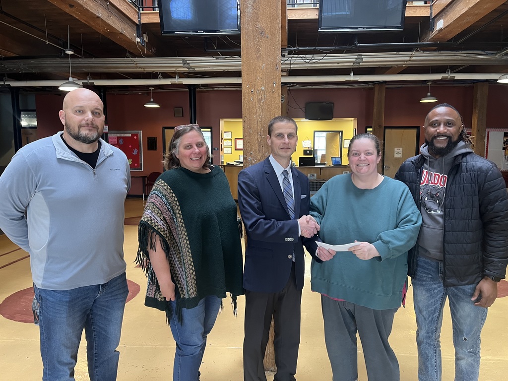 From left to right, Jeremy Martin, Shelly Harris, Keith Epstein, Autumn Snow, and Jamel Jones. Epstein is handing snow a check and shaking her hand. in the RCS lobby