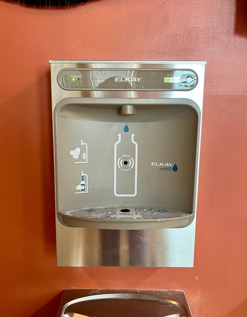 A water bottle fillers on an orange wall.