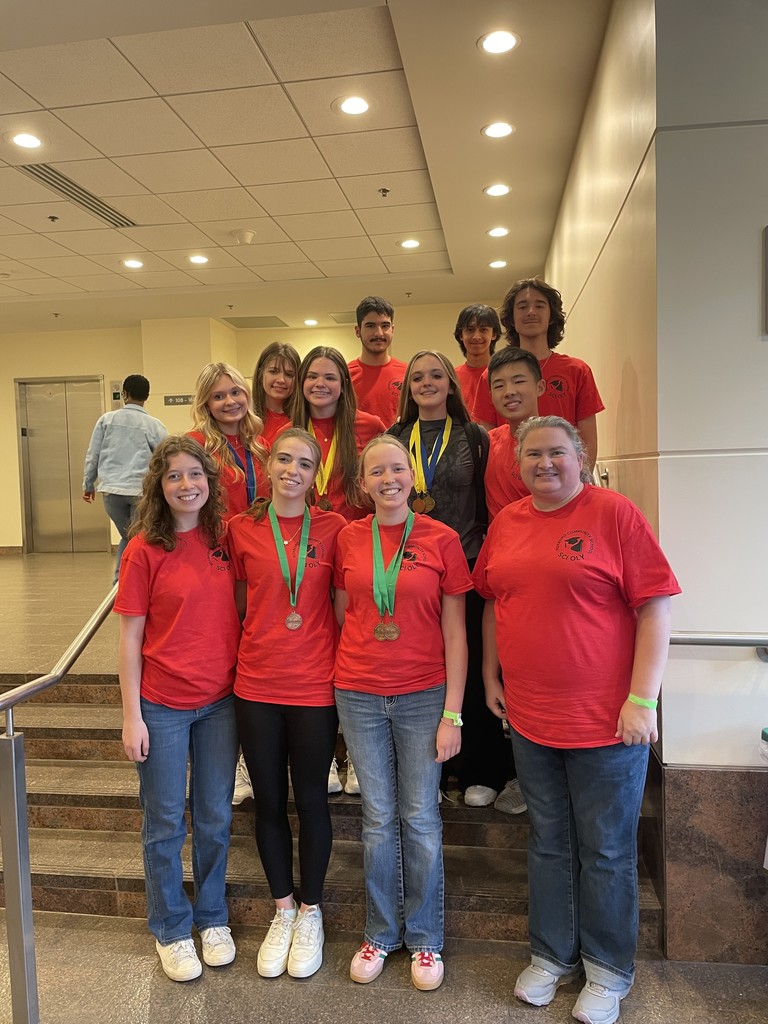 The RCS science olympiad team all in red t-shirts after the competition, with multiple students wearing medals.
